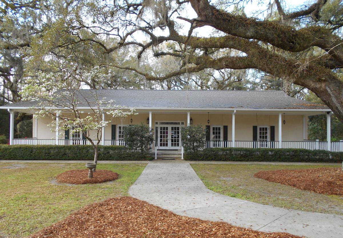 Exterior of restored yellow house next to grand oak with spanish moss